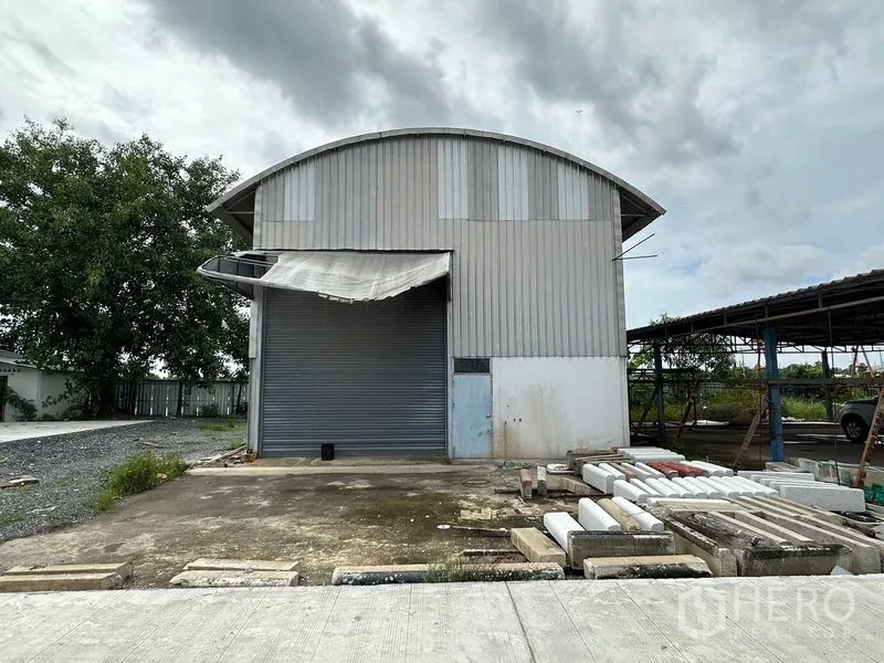 Factory for rent in Lam Luk Ka, Pathum Thani - Secondary steel shed with roller shutter door beside open yard.