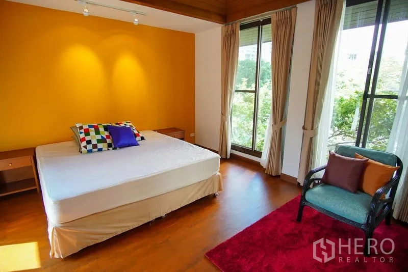 Townhouse for rent in Watthana, Bangkok - Sunny bedroom with yellow accent wall and corner windows.