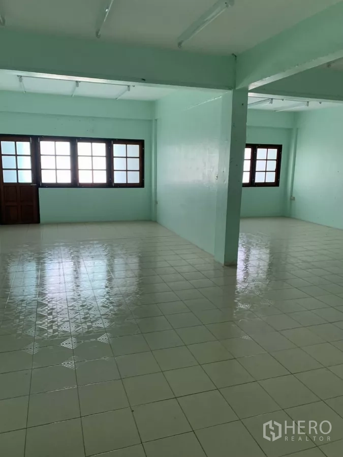 Shophouse for rent in Suan Luang, Bangkok - Spacious open-plan level with central columns, glossy patterned tiles and multiple windows.