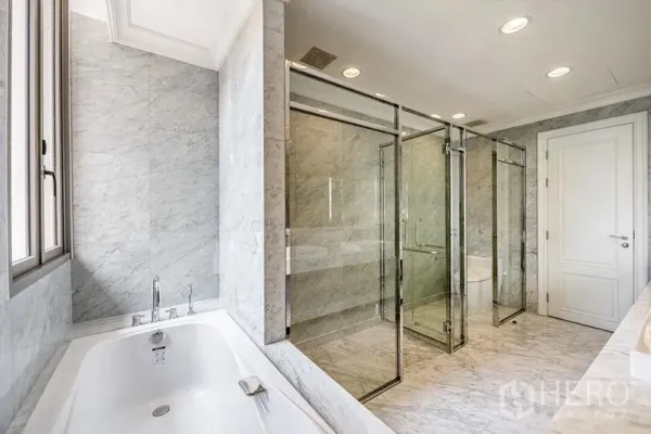 Townhouse for rent in Khlong Toei, Bangkok - Spacious marble bathroom featuring a soaking tub and twin glass-enclosed showers with recessed lighting.
