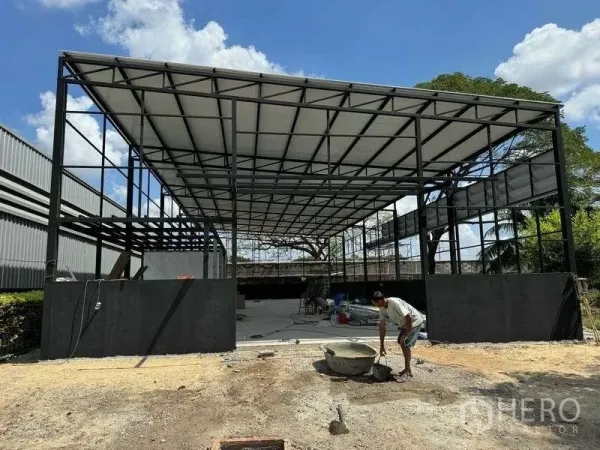 Warehouse for rent in Mueang Pathum Thani, Pathum Thani - Front view of a wide-span warehouse shell with metal roofing and open frontage.
