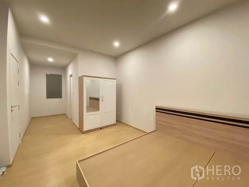 Townhouse for rent in Prawet, Bangkok - Secondary bedroom with platform bed and freestanding wardrobe.