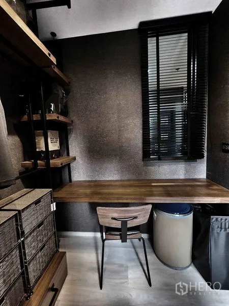 Condominium for sale in Pathum Wan, Bangkok - Compact home office corner with wooden desk, chair, and window blinds.