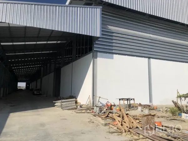 货栈 出租在Bang Phli, Samut Prakan - 仓库侧边带顶装卸区，宽阔车道与堆放的建筑材料。