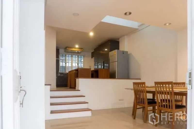 Townhouse for rent in Bang Kapi, Bangkok - Open-plan dining and kitchen area connected by short steps with recessed ceiling lights.