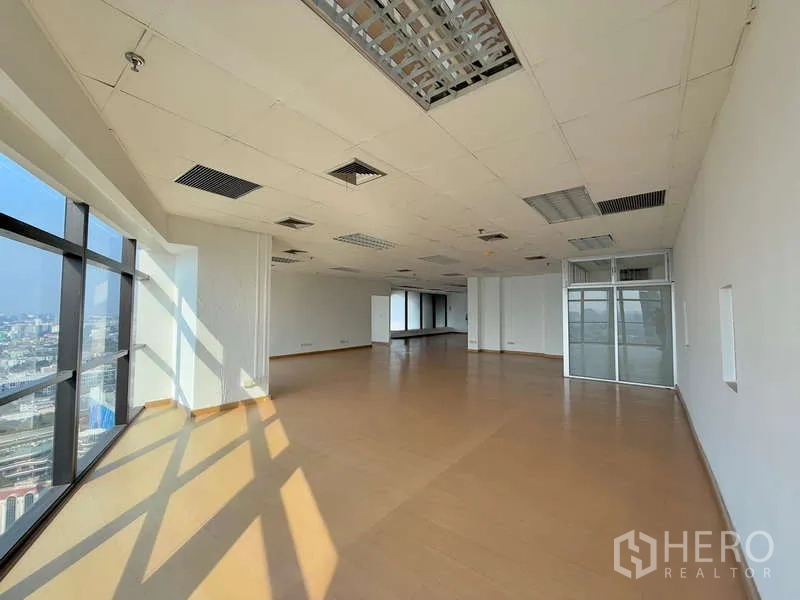 Office Space for rent in Chatuchak, Bangkok - Open-plan office with wood floors, drop ceiling lighting, and corner windows overlooking the Bangkok skyline.