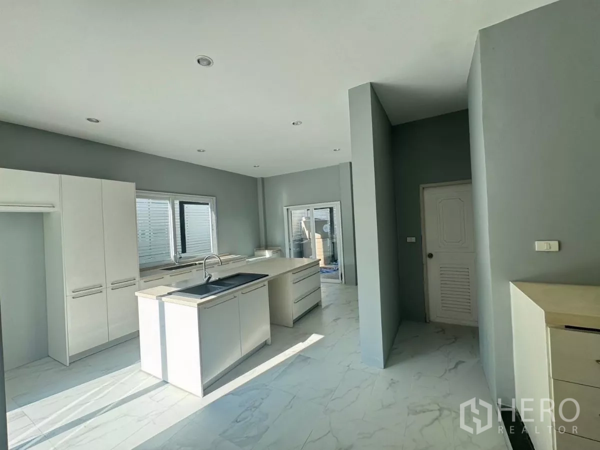 Detached House for rent or sale in Prawet, Bangkok - Bright modern kitchen with island, white cabinetry and large windows.
