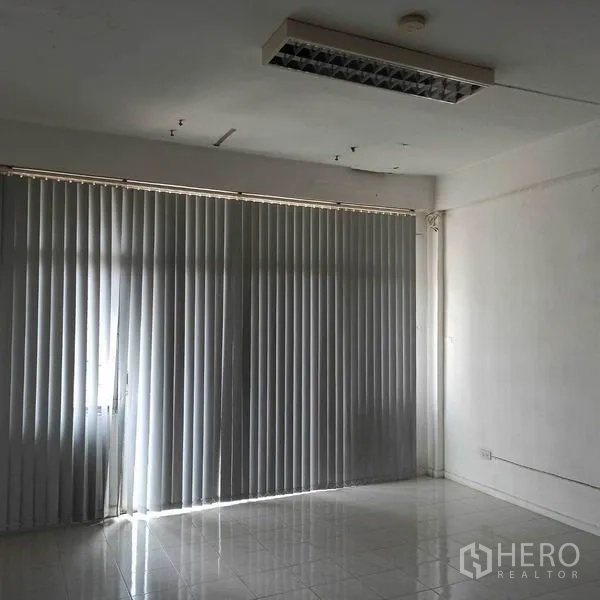 Shophouse for rent in Khlong Toei, Bangkok - Empty shophouse room with tiled floor and vertical blinds covering large windows.