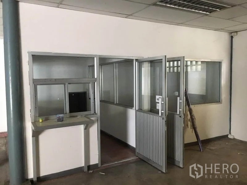 Warehouse for rent in Prawet, Bangkok - Ground-floor partitioned office rooms with glass windows and metal doors inside the warehouse.