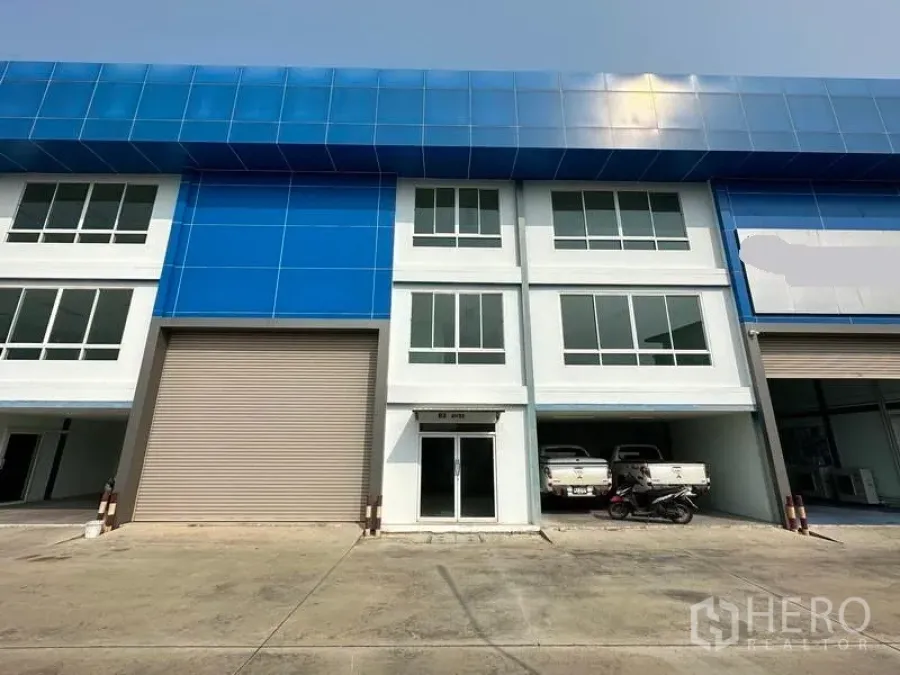 Warehouse for rent in Bang Phli, Samut Prakan - Front view of a modern warehouse with blue cladding, a large roller shutter and glass office entry in a secure compound.