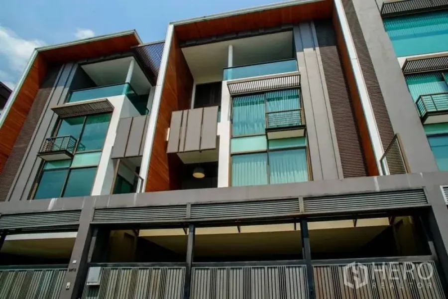 Townhouse for rent or sale in Watthana, Bangkok - Modern multi-storey townhouse facade with glass balconies and gated parking