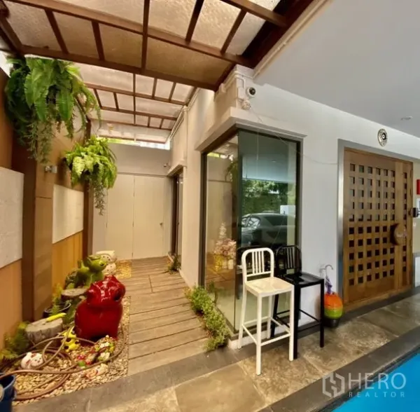 带办公室的家 出租或出售在Yan Nawa, Bangkok - 带天窗的门廊通道，木质步道与小型绿植花园，旁为玻璃转角。