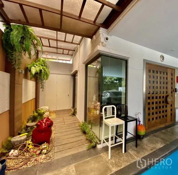 带办公室的家 出租或出售在Yan Nawa, Bangkok - 带天窗的门廊通道，木质步道与小型绿植花园，旁为玻璃转角。