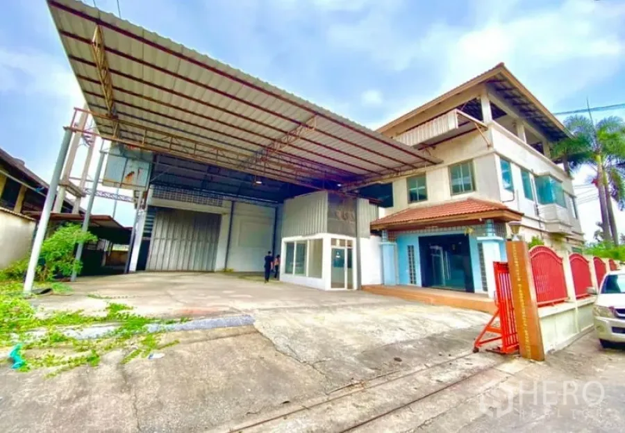 Warehouse for rent or sale in Mueang Samut Sakhon, Samut Sakhon - Warehouse exterior with a covered loading bay, multi-storey office building, wide driveway, and gated entrance.