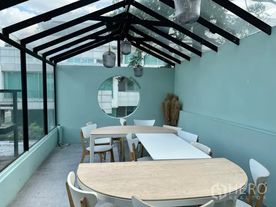 Retail Space for rent in Watthana, Bangkok - Glass-roof conservatory dining area with wooden tables, mint walls, circular window and pendant lighting.
