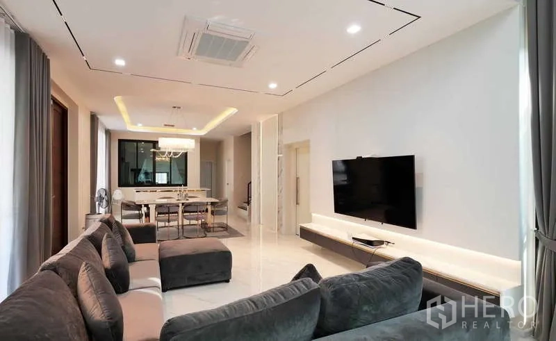 Detached House for rent or sale in Thanyaburi, Pathum Thani - Alternate view of lounge and dining with chandelier lighting and wide curtains.