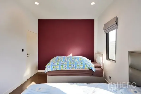 Detached House for rent or sale in Bang Kapi, Bangkok - Cozy secondary bedroom featuring a maroon accent wall, side window and warm wood floors.