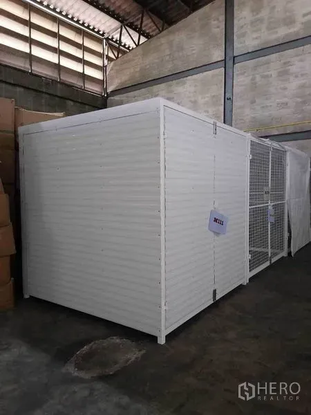 Factory for rent in Bang Phli, Samut Prakan - Secure white storage cage within a high-ceiling warehouse space.