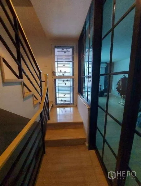 联排别墅 出租在Bang Phli, Samut Prakan - 室内走廊，木楼梯与金属扶手，玻璃隔断通向起居区。