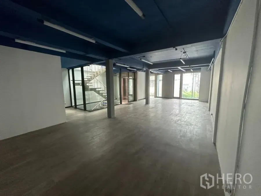 Office Space for rent in Watthana, Bangkok - Long open workspace featuring large windows and a central glass stairwell enclosure.