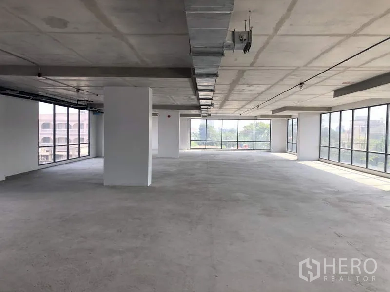 Office Space for rent in Suan Luang, Bangkok - Bright corner office zone with panoramic glazing and unfinished concrete floor.