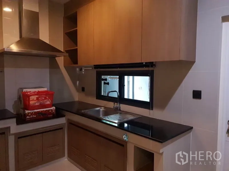 Detached House for rent in Bang Kapi, Bangkok - Separate kitchen with black granite countertops, double sink, light-wood cabinetry, and a window.