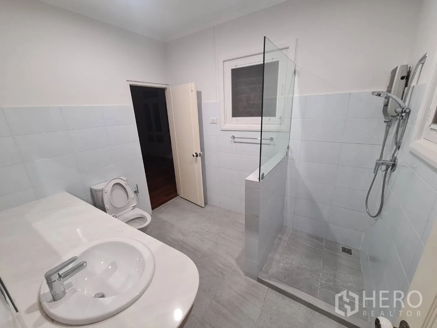 Detached House for rent in Khlong Toei, Bangkok - Bright bathroom with glass-partition shower and long counter.