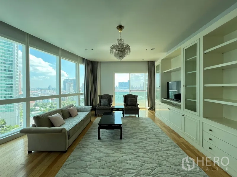 Condominium for rent in Khlong Toei, Bangkok - Bright living room with floor-to-ceiling windows, city skyline views, built-in shelves and a chandelier.