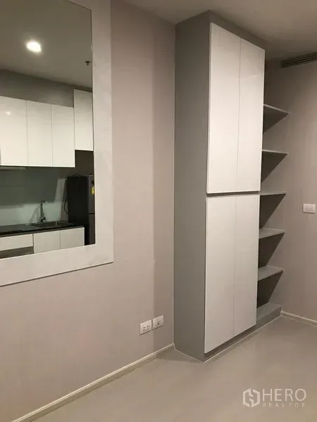 Condominium for rent in Pathum Wan, Bangkok - Built-in tall cabinet and open corner shelves in a neutral-toned room