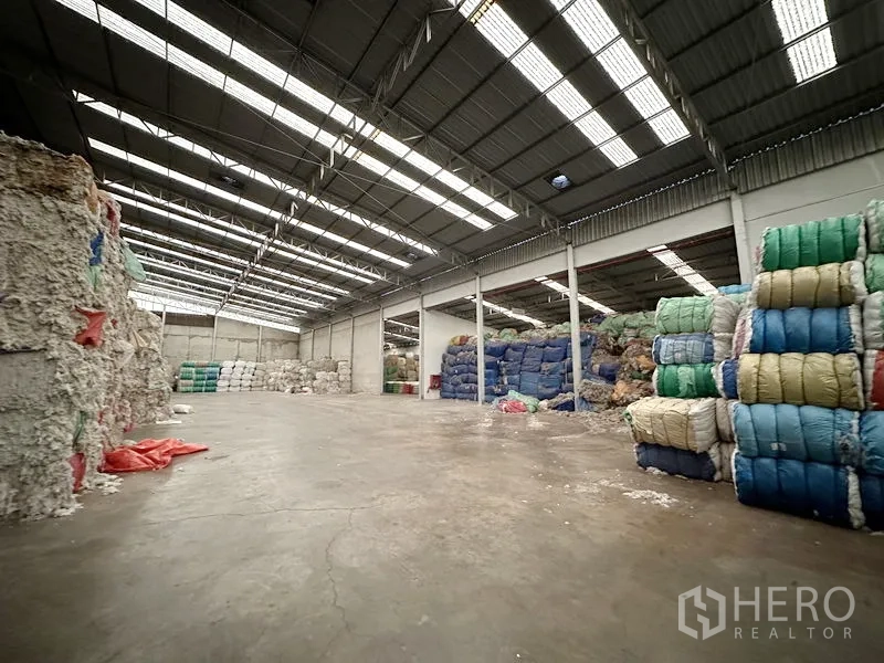 Factory for rent in Bang Bua Thong, Nonthaburi - Spacious warehouse interior with high ceiling, skylights and wide concrete floor for storage.