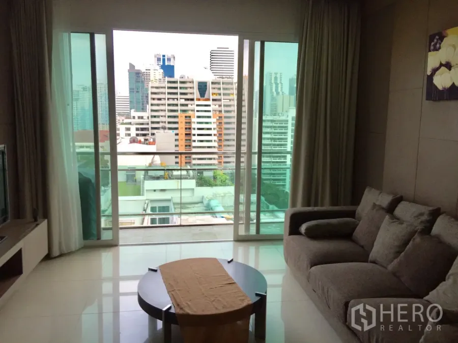 公寓 出租在Watthana, Bangkok - 明亮客厅，沙发与茶几，落地推拉门连接阳台，可眺望曼谷城市景观。