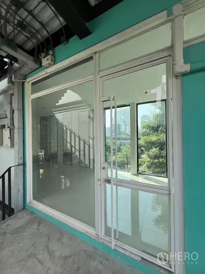 Retail Space for rent in Watthana, Bangkok - Third-floor retail storefront with glass door, turquoise facade and stair access overlooking greenery.