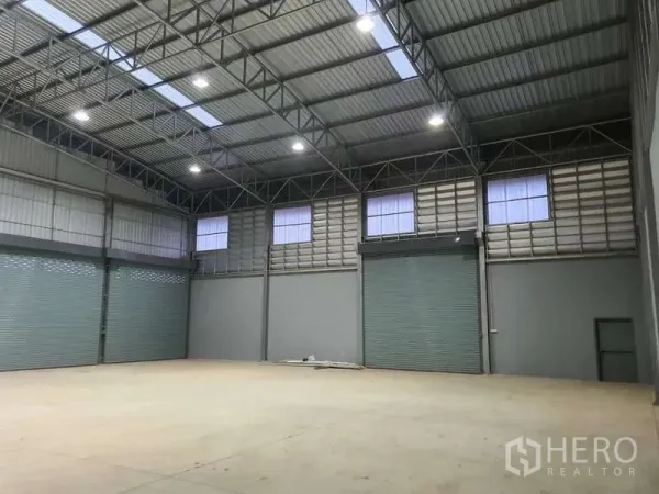 Warehouse for rent in Khlong Luang, Pathum Thani - Wide industrial space with multiple loading doors, bright LED lights and a high-clearance ceiling.