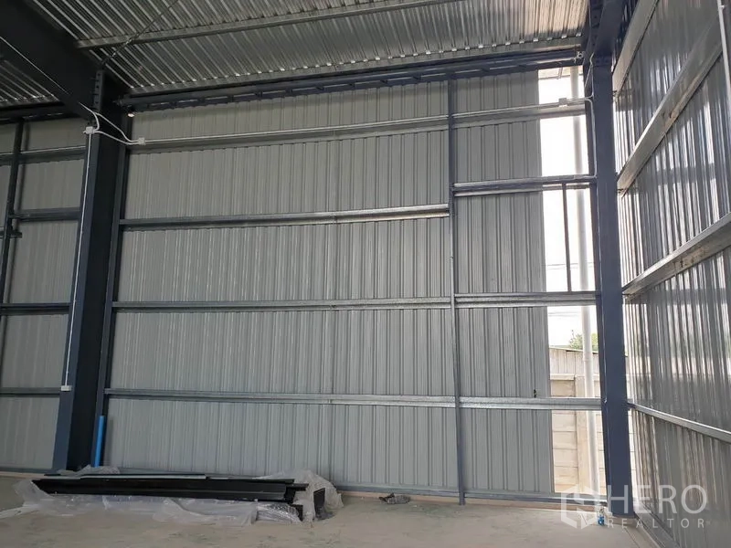 Warehouse for rent in Lam Luk Ka, Pathum Thani - Close-up of interior corrugated metal wall and steel beams inside the warehouse.