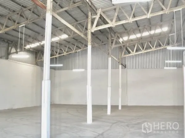 工厂 出租在Bang Pakong, Chachoengsao - 高挑仓库分区，外露屋梁、吊灯与平整混凝土地面。