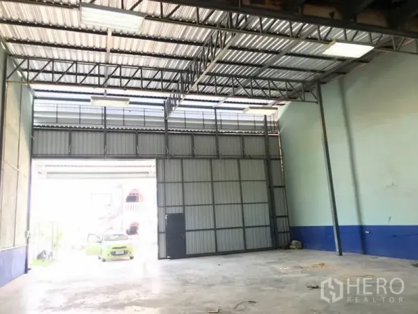 Warehouse for rent in Lat Krabang, Bangkok - High-ceiling warehouse interior with steel truss roof, large sliding door and concrete floor in Lat Krabang.