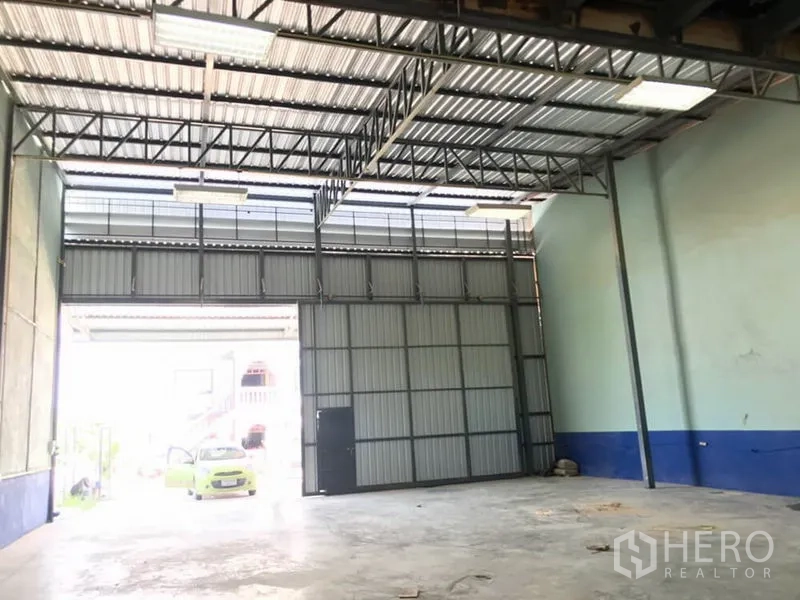 Warehouse for rent in Lat Krabang, Bangkok - High-ceiling warehouse interior with steel truss roof, large sliding door and concrete floor in Lat Krabang.