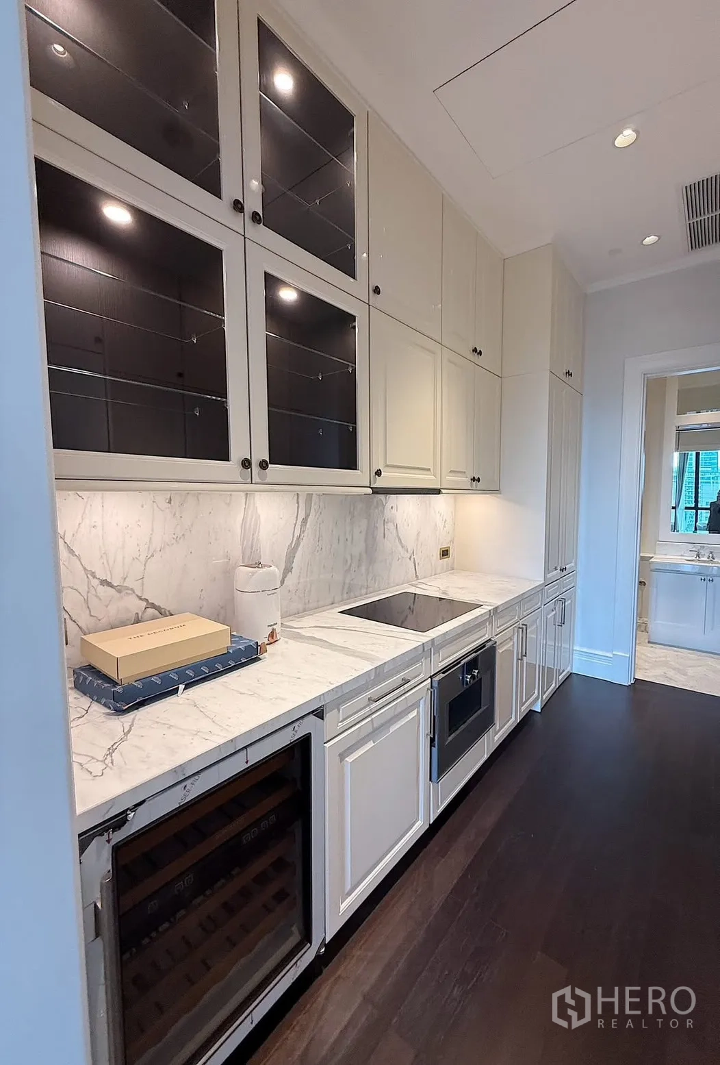 Condominium for rent or sale in Pathum Wan, Bangkok - Close-up of the kitchen showing induction hob, sink, oven, and glass-front upper cabinets.