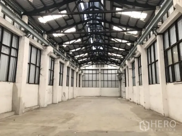 货栈 出租在Khlong Luang, Pathum Thani - 仓库内部空间宽敞，山墙高顶、钢桁架、侧窗与混凝土地坪。