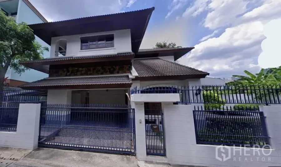 Detached House for rent in Watthana, Bangkok - Front exterior view of the gated house with tiled roof.