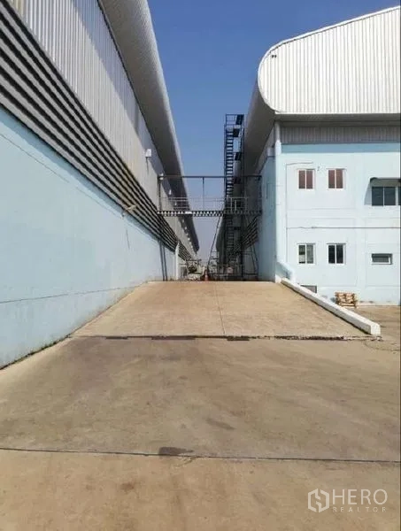 Warehouse for rent in Nong Chok, Bangkok - Concrete ramped driveway between warehouse buildings providing easy vehicle access.
