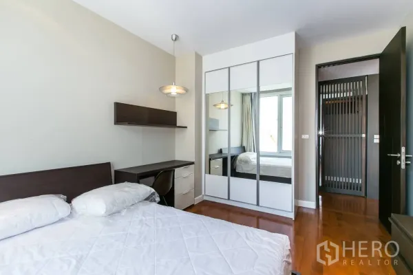 Condominium for rent or sale in Khlong Toei, Bangkok - Guest bedroom with mirrored wardrobe, study desk and pendant light.
