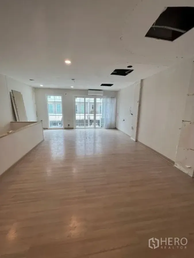 Home Office for rent - Spacious open-plan room with light wood flooring, recessed lights, and balcony doors with sheer curtains.