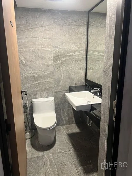 Retail Space for rent in Watthana, Bangkok - Modern restroom finished in gray stone tiles with white sink and toilet.