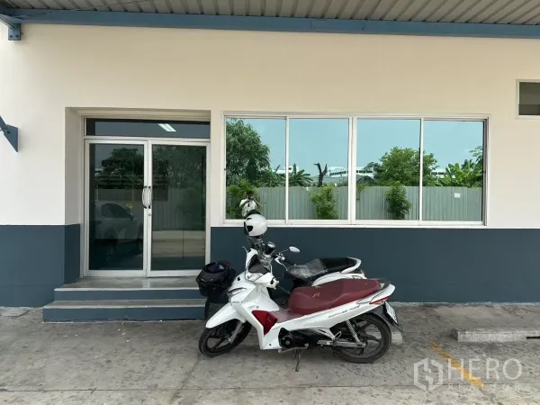 Factory for rent in Bang Phli, Samut Prakan - Front office entrance with sliding glass door and windows under an awning; motorcycles parked outside.