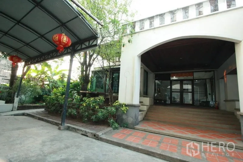 Detached House for rent in Bang Phli, Samut Prakan - Front porch with arched entry, terracotta steps, greenery and a covered parking area.