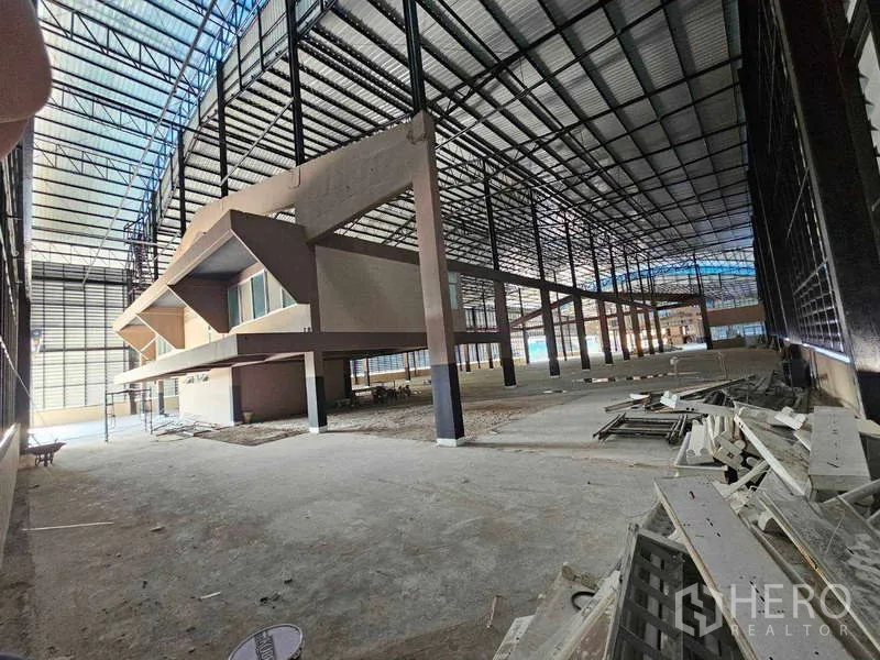 Factory for rent in Chon Buri - Factory interior from another angle featuring mezzanine offices and steel columns.