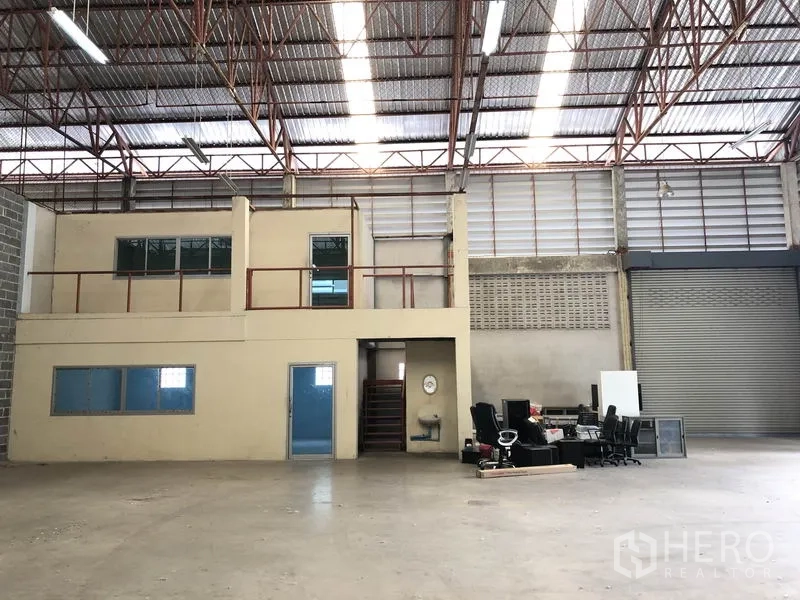 Warehouse for rent in Khlong Sam Wa, Bangkok - Interior hall highlighting the mezzanine office with staircase, overhead lighting and expansive clear floor area.