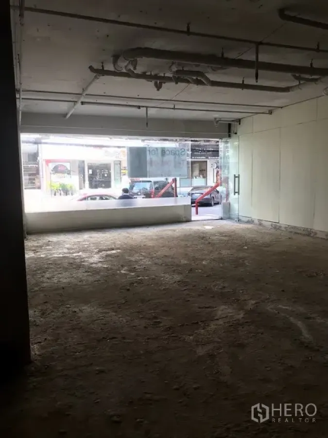 Retail Space for rent in Khlong Toei, Bangkok - Unfinished street-facing retail unit with wide glass frontage and glass door allowing natural light.