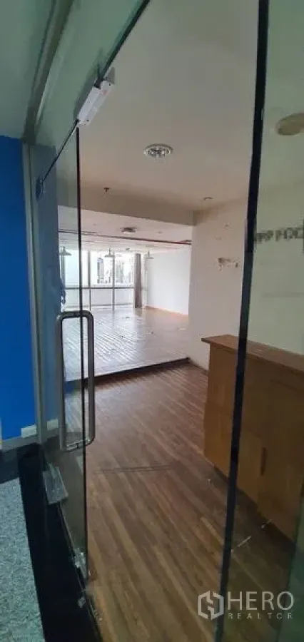 办公空间 出租在Watthana, Bangkok - 从玻璃门望入明亮办公室，木地板及接待柜台一览。